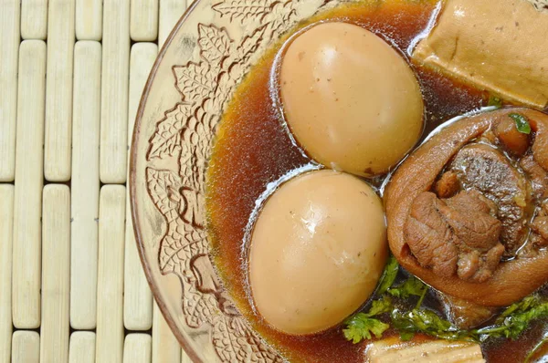 Uovo sodo con coscia di maiale in zuppa di erbe marroni su ciotola di vetro — Foto Stock