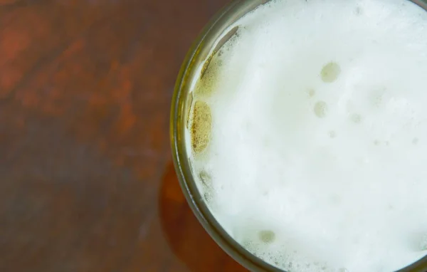 冷たいビールと木製の背景上にガラスに泡 — ストック写真