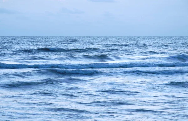 Surfe de água do mar desfocado para a praia no pôr do sol — Fotografia de Stock