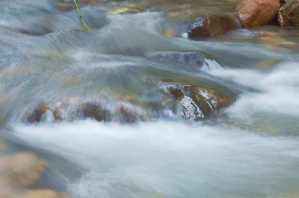 Verschwommenes Wasser, das auf den Felsen fließt und Welle, die im Fluss plätschert — Stockfoto