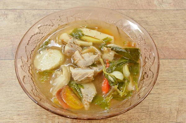 Hueso de cerdo caliente y picante con tamarindo y sopa de hierbas tailandesas en un tazón de vidrio —  Fotos de Stock