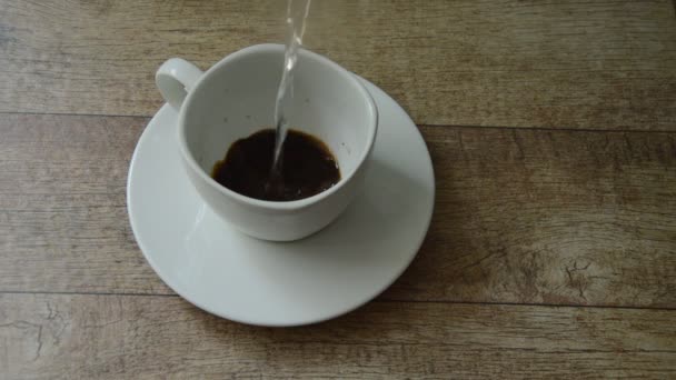 mélange de café noir par l'eau chaude versant sur le verre 