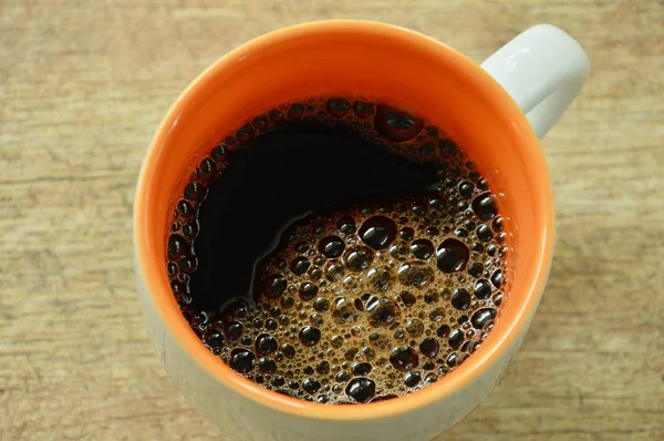 Café caliente negro con burbuja flotando en la taza en la mesa — Foto de Stock