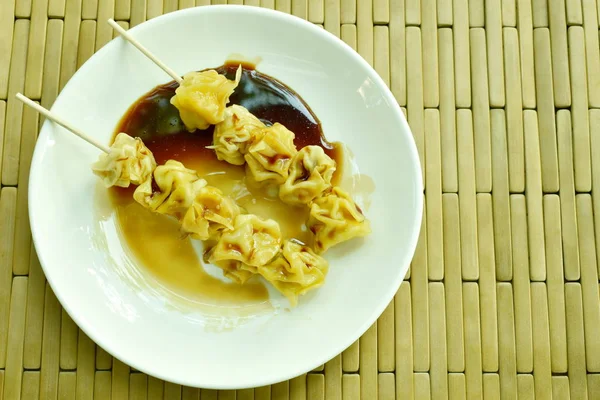 Chinese dumpling stabbing wooden stick dressing soy sauce on plate