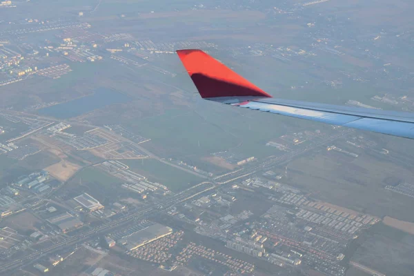 Ala plana a través del marco de la ventana y vista de la ciudad en tierra — Foto de Stock