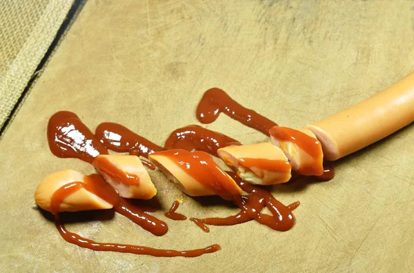 Long pork sausage stuffed cheese and ham slicing dressing ketchup on wooden chop block — Stock Photo, Image