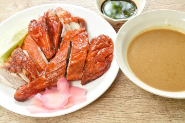  Kızarmış ördek eti ve tatlı soya sosunu tabağa bandıran zencefil turşusu.