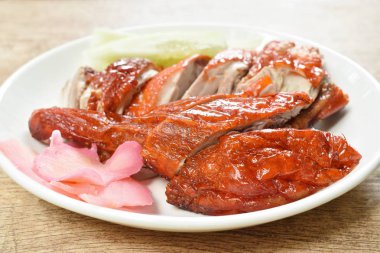  Kızarmış ördek eti ve tatlı soya sosunu tabağa bandıran zencefil turşusu.