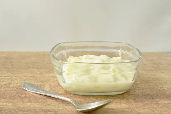 Yogur de frutas en tazón de vidrio y cuchara de plata en la mesa —  Fotos de Stock