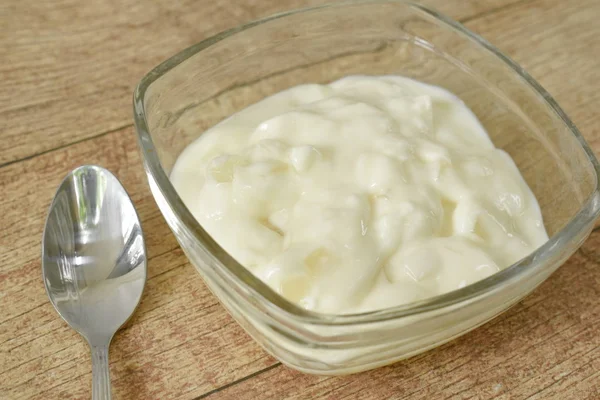 Фруктовий йогурт в скляній мисці і срібна ложка на столі — стокове фото