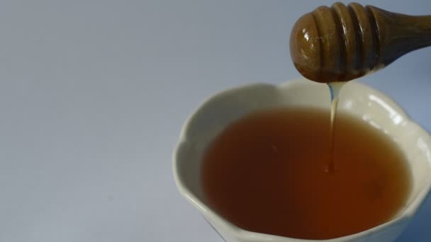 白い背景でカップに木製のスクープドロップの蜂蜜 — ストック動画