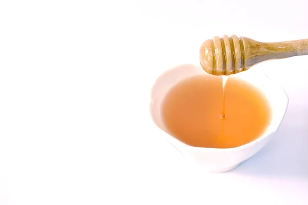 Miel sur cuillère en bois goutte à tasse en fond blanc — Photo