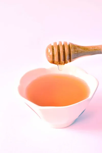 Miel en cucharada de madera gota a taza en fondo blanco — Foto de Stock