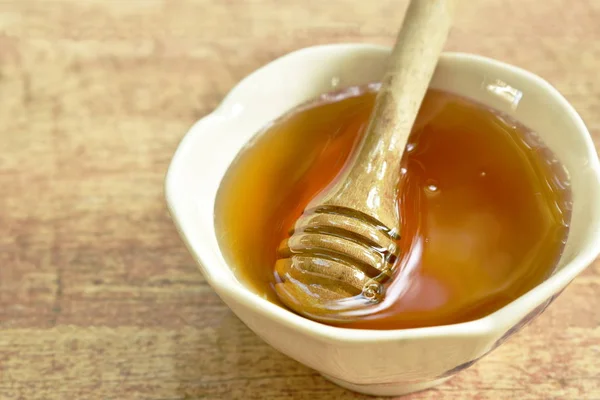 Miel y cuchara de madera en taza en la mesa — Foto de Stock