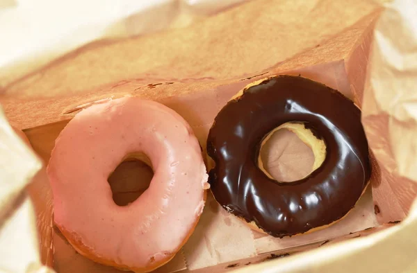 chocolate and strawberry donuts packing in brown paper bag