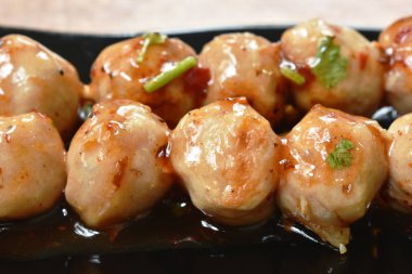  siyah plaka üzerinde ahşap sopa soyunma baharatlı ve tatlı sos bıçaklama ızgara domuz tendon et topu 