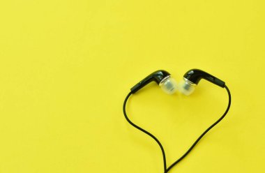  sarı köpük tahta arka plan üzerinde kalp şekli düzenleme mobil telefon ile conecting için siyah kulaklık