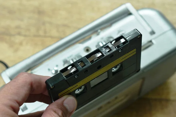 Hand holding black cassette tape with radio background — Stock Photo, Image