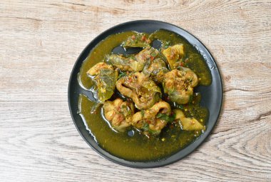 Baharatlı kızarmış yayın balığı körili ve tabağında bitki var.