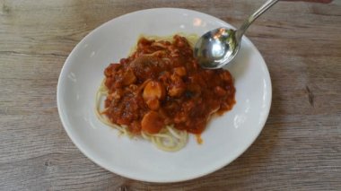 Kızarmış spagetti sosisli, domuz pirzolası ve ketçaplı, çatallı tabak.