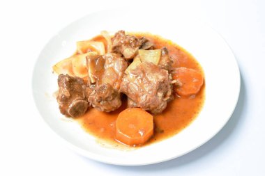 Kızarmış domuz kemiği, dilimlenmiş havuç ve soğanlı, sulu ve ekşi soslu tabak.