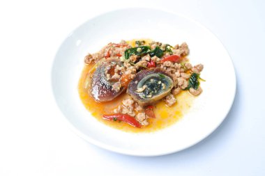 Dilimlenmiş siyah haşlanmış yumurta soslu baharatlı domuz pirzolası ve fesleğen yaprağı.