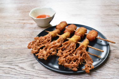 Kızarmış Enokitakeor iğneli mantar unlu hamur tatlısı ve ahşap sopaya batırılmış domuz pastırması tatlı acı biber sosu.