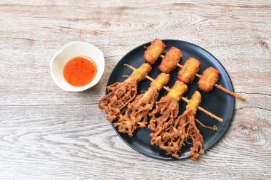 Kızarmış Enokitakeor iğneli mantar unlu hamur tatlısı ve ahşap sopaya batırılmış domuz pastırması tatlı acı biber sosu.