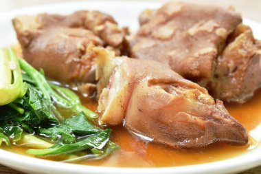 Haşlanmış domuz budu ve ayakla Çin lahanası ve tabakta siyah bitki çorbası.