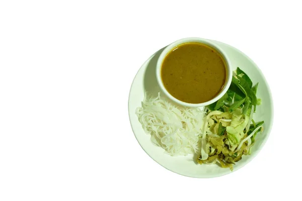 rice noodles dressing with meat ball fish coconut milk curry sauce and fresh vegetable on plate