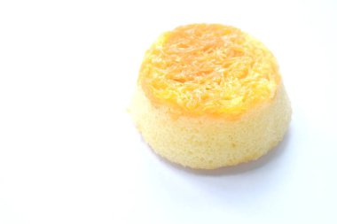 Beyaz arka planda altın sarısı ipliklerle kaplı daire şeklinde pasta.