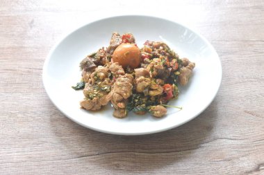 Baharatlı biberli kızarmış tavuk eti ve tabağında fesleğen yaprağı olan çift yumurta.