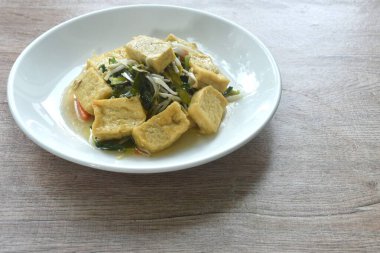 Kızarmış fasulye filizi ve garliv soğanı. Tabakta da sarı tofu vejetaryen yemeği. 