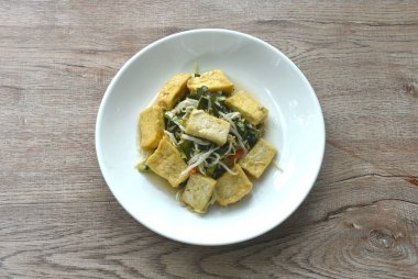 Kızarmış fasulye filizi ve garliv soğanı. Tabakta da sarı tofu vejetaryen yemeği. 