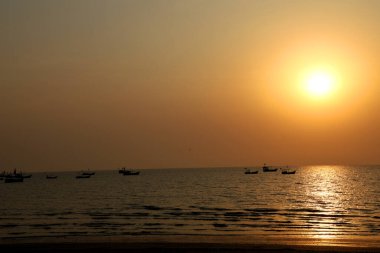 İnsanların doldurduğu güzel bir sahilde gün batımı.