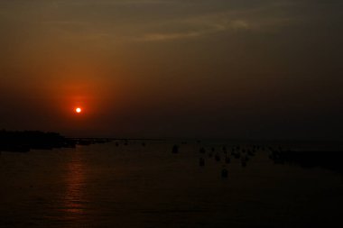 İnsanların doldurduğu güzel bir sahilde gün batımı.