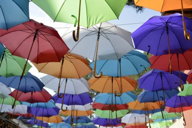 Sokakta güneşten korunmak için çeşitli renklerde şemsiyeler.