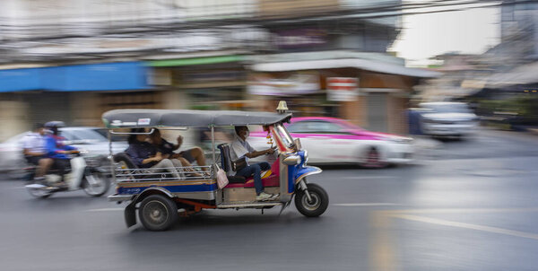 Bangkok, Thailand - February 28th, 2020: A "tuk-tuk", the Thailand 's famous old fashioned taxi, in motion on a Bangkok street.