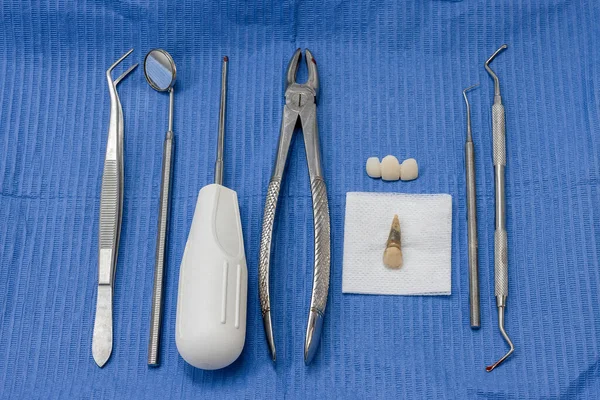 Dental instruments after a tooth extraction with the extracted tooth and a provisional bridge to replace it.