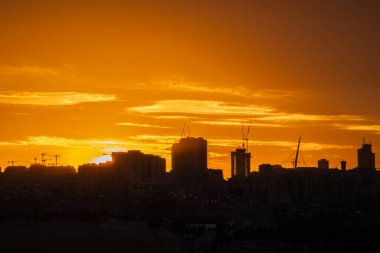 Ateşli bir gündoğumu, İsrail 'in Kudüs silueti, altın ışıkta, siluetli vinçler ve yüksek mertebelerle çarpıcı, parıldayan gökyüzüne karşı yıkanıyor..