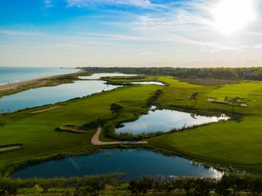 Okyanus boyunca golf sahası gün batımı yapıyor 