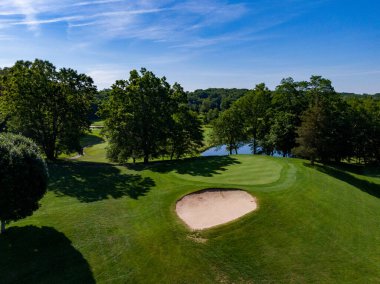 Bayrağın arkasında gölet olan deliğe golf atışı
