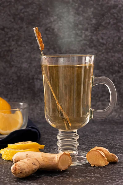 A glass of hot steaming ginger and lemon tea on dark background — Stock Photo, Image