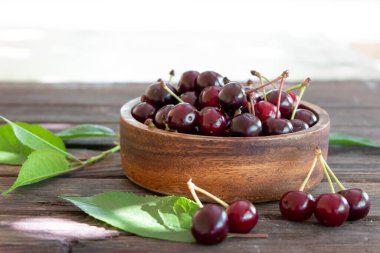 Taze kirazlar ahşap bir kasede, eski ahşap bir arka planda fotokopi alanı ile.