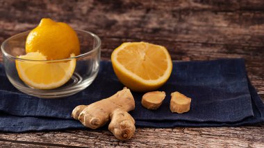 Zencefil kökü parçaları ve limon dilimleri, koyu ahşap arka planda, sıcak zencefil çayı için malzeme olarak.