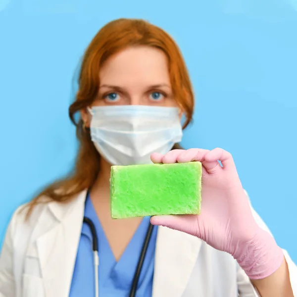 Virologist doctor hand with a bar of soap on a blue background,