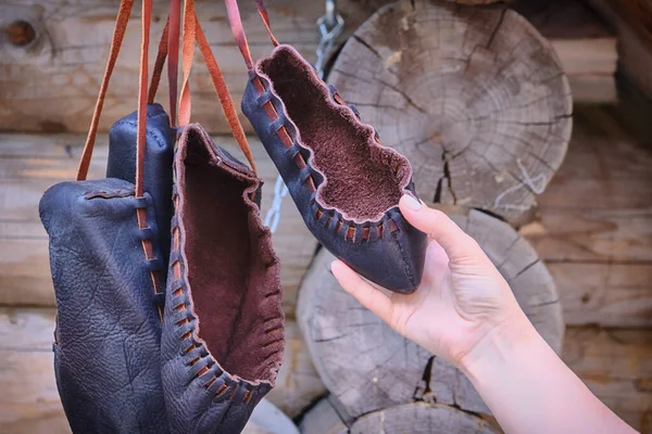 Woman holding a retro Shoe made of rough leather. The shoes are vintage style from primitive material.