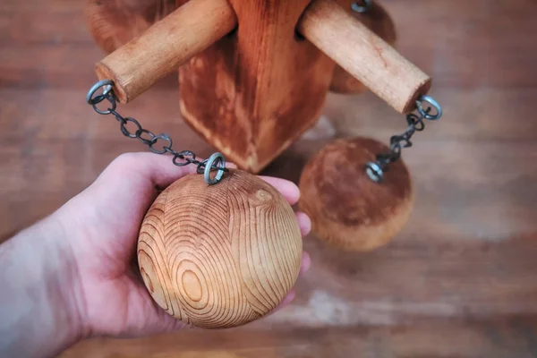 Mechanism with wooden balls on a chain. Hand holding a large wooden ball.