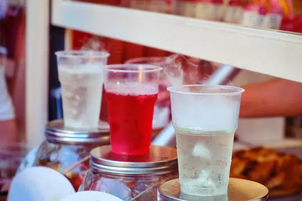 Sale of cold drinks in a street shop. Soda in plastic cups on the counter of the city cafe. Drinks with ice in warm weather.