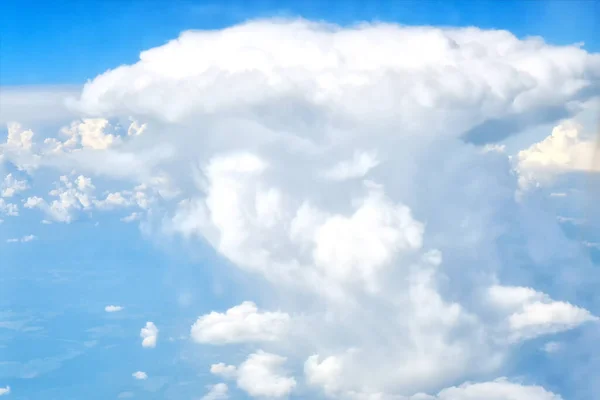 A big white cloud like a mushroom from a nuclear explosion. An object-like cloud in the blue sky.